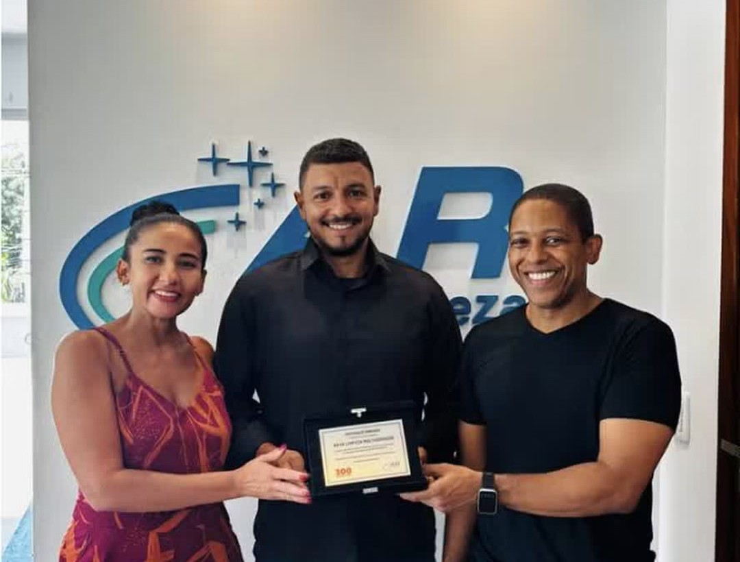 Sócios da AR de Limpeza Multiserviços com a placa de reconhecimento na sede da empresa